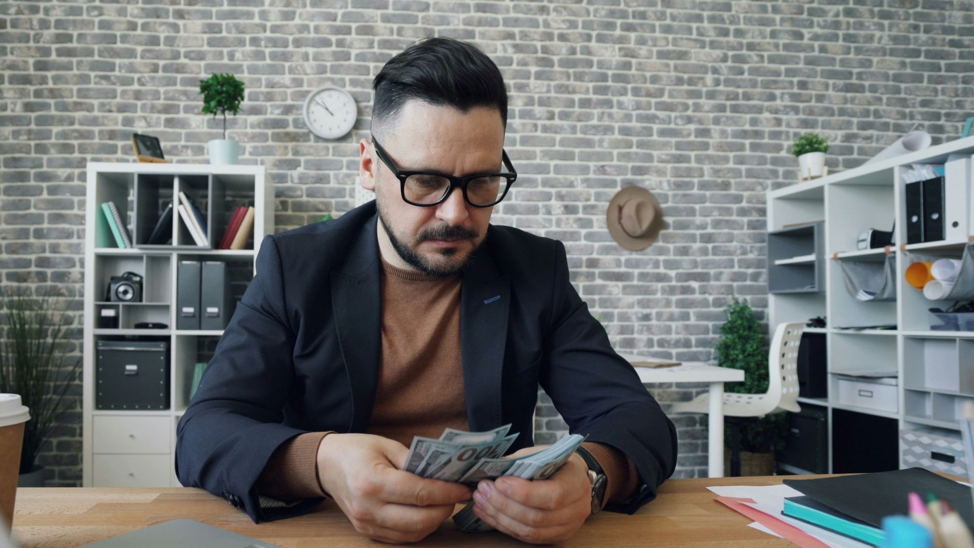 a man sitting at a table with a laptop and money