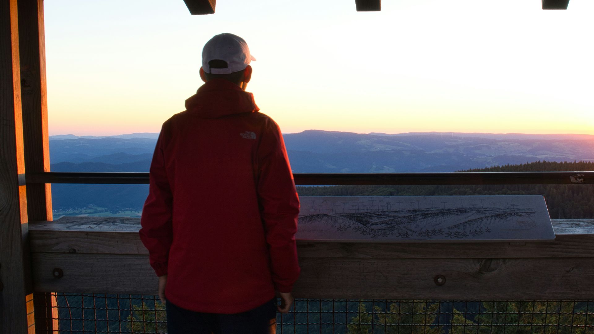 a person standing in front of a window looking out at the water