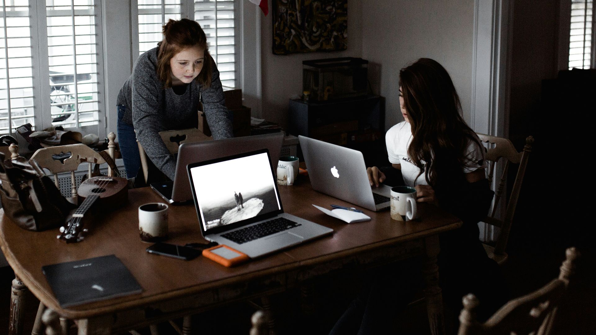 women using laptop on brown wooden table
