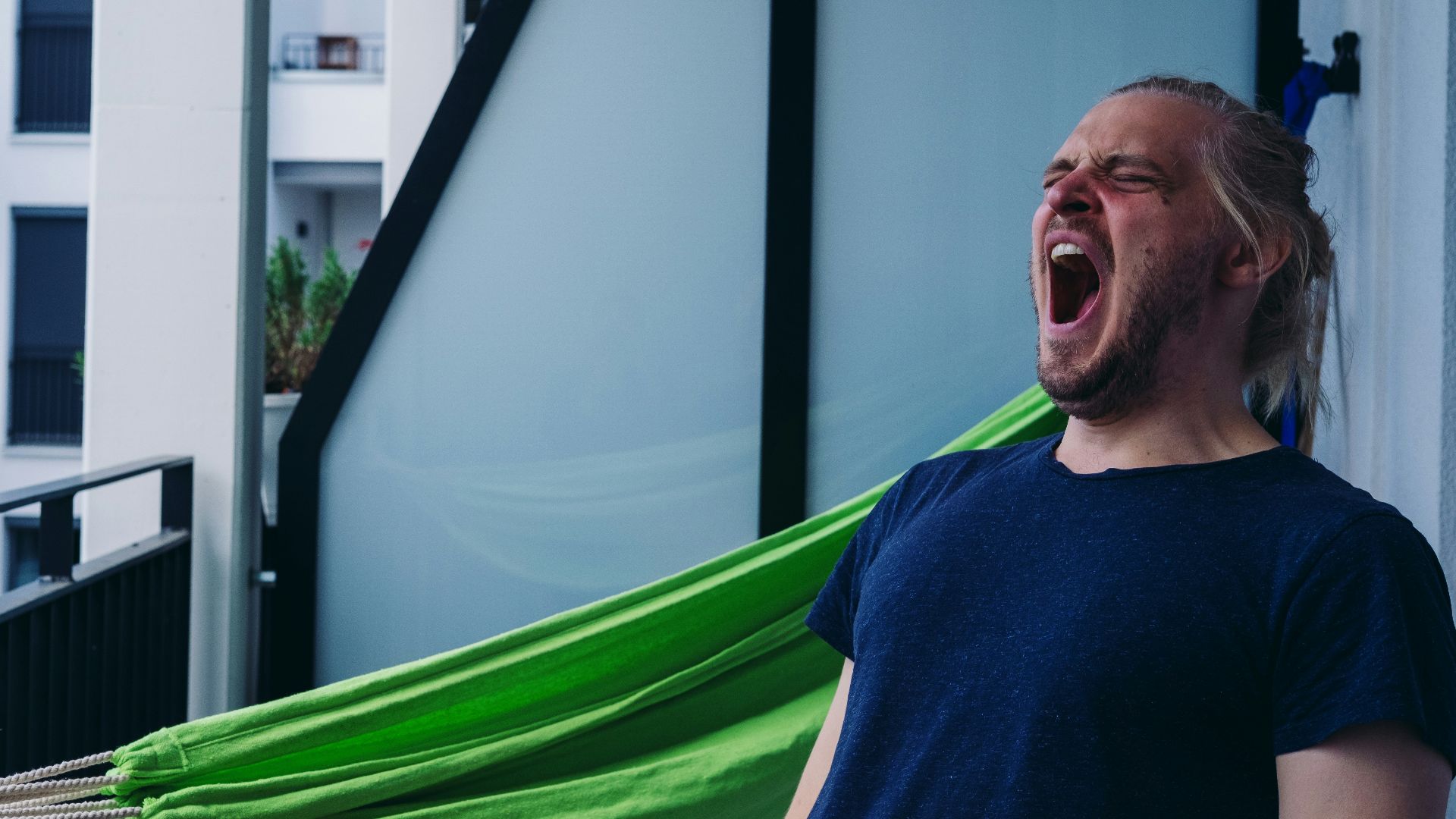 man in blue crew neck shirt standing beside green hammock