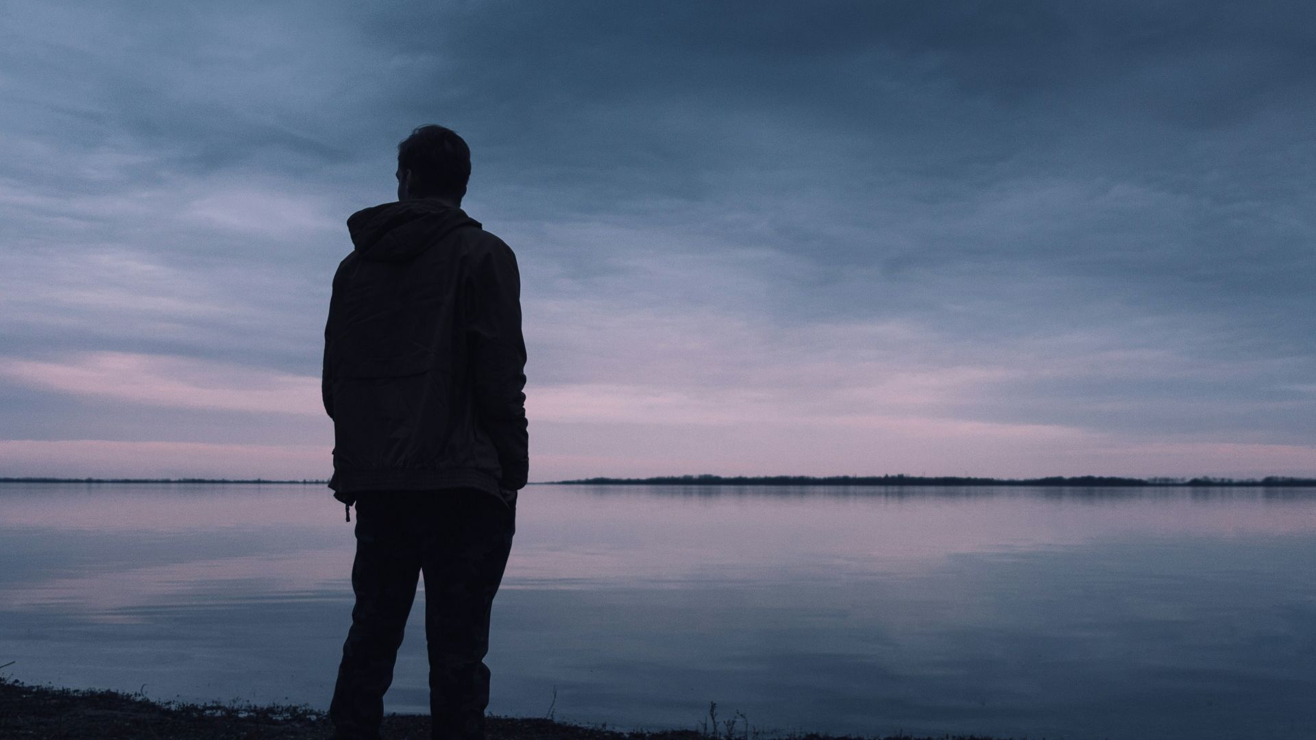 silhouette of man standing near body of water