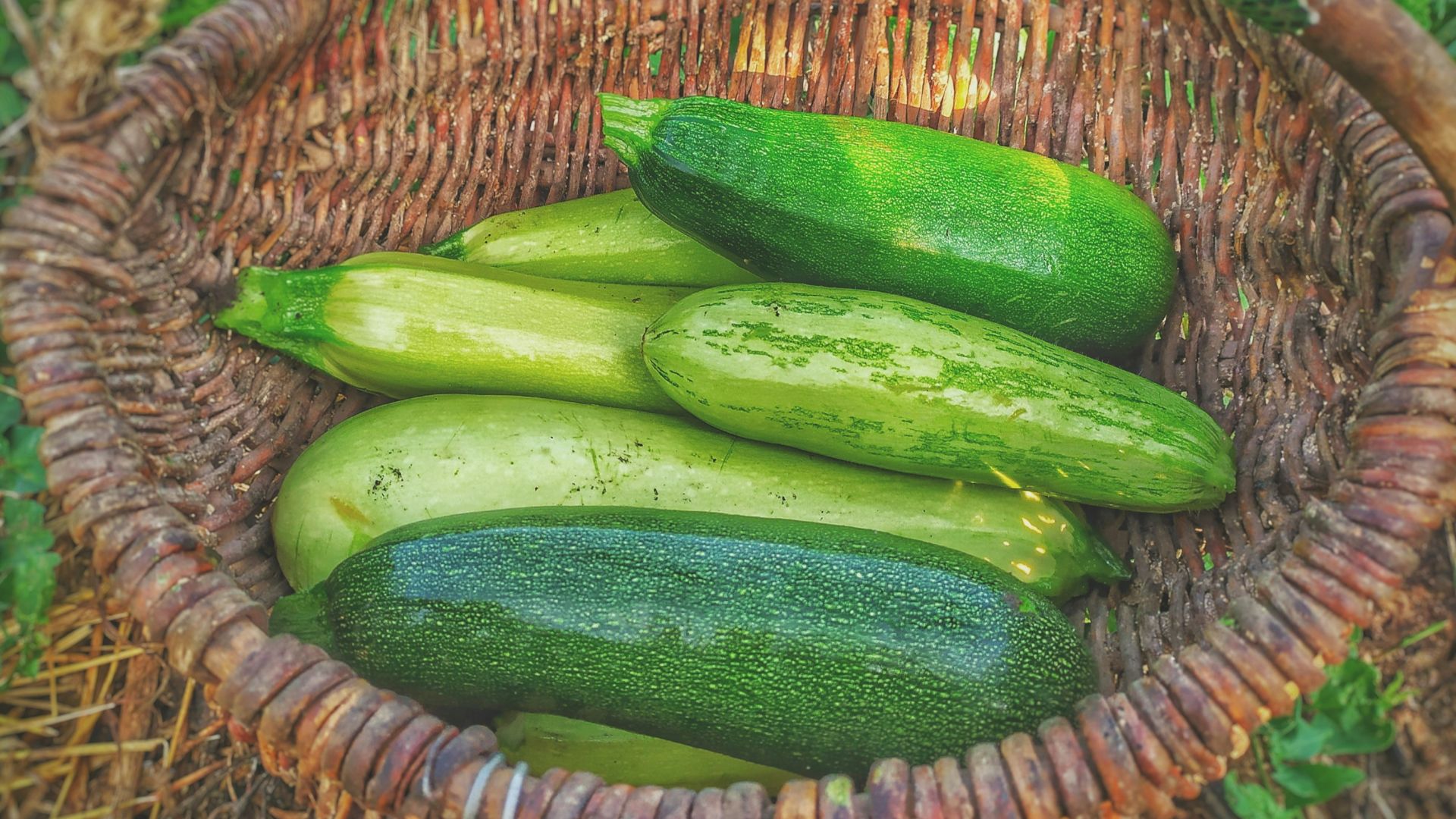 green cucumbers on round brown wicker basket