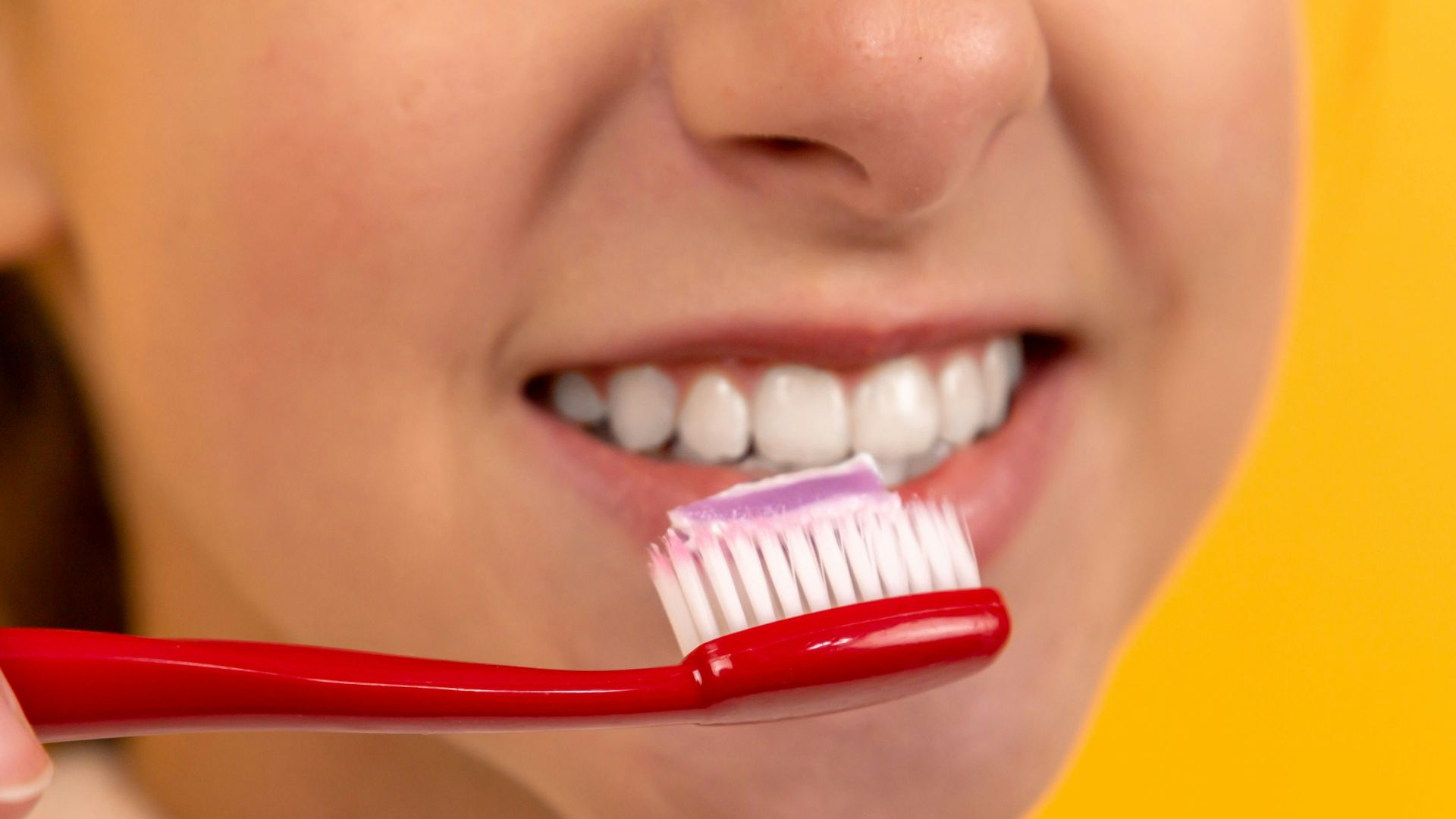 girl with red and white toothbrush in mouth