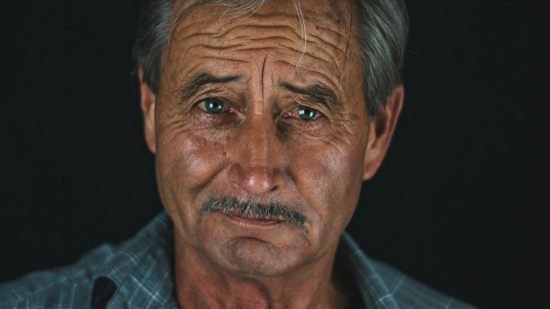 low-light photography of man wearing blue collared shirt