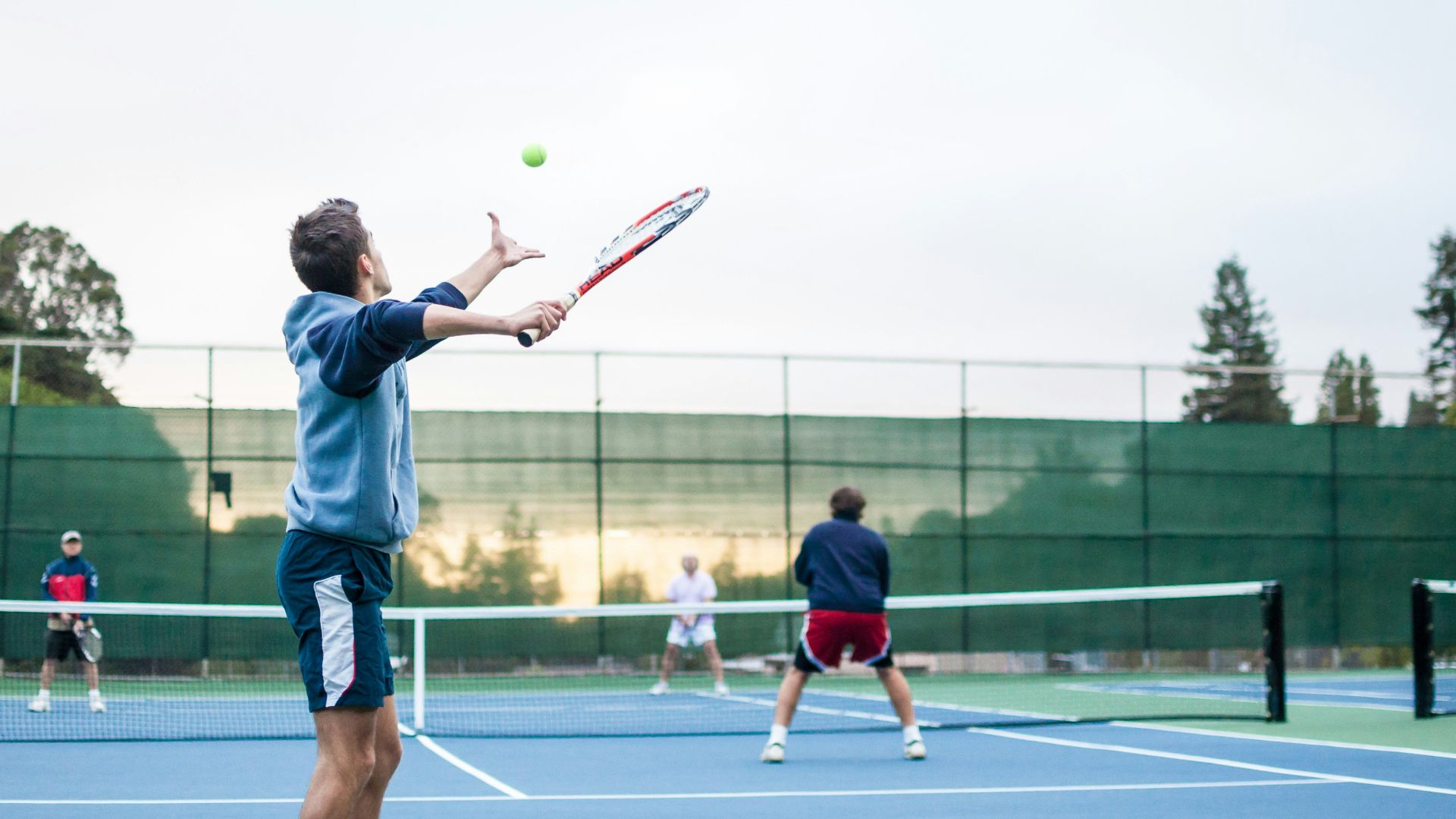 four men playing double tennis during daytime