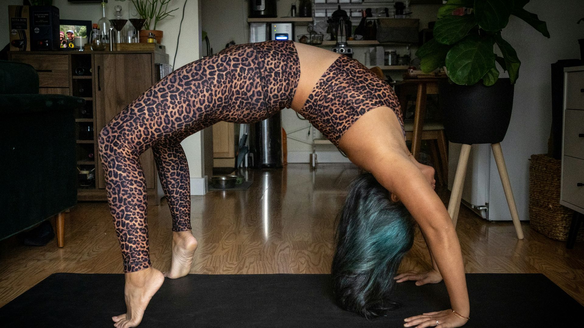 woman in black and white polka dots leggings bending her body on brown wooden table