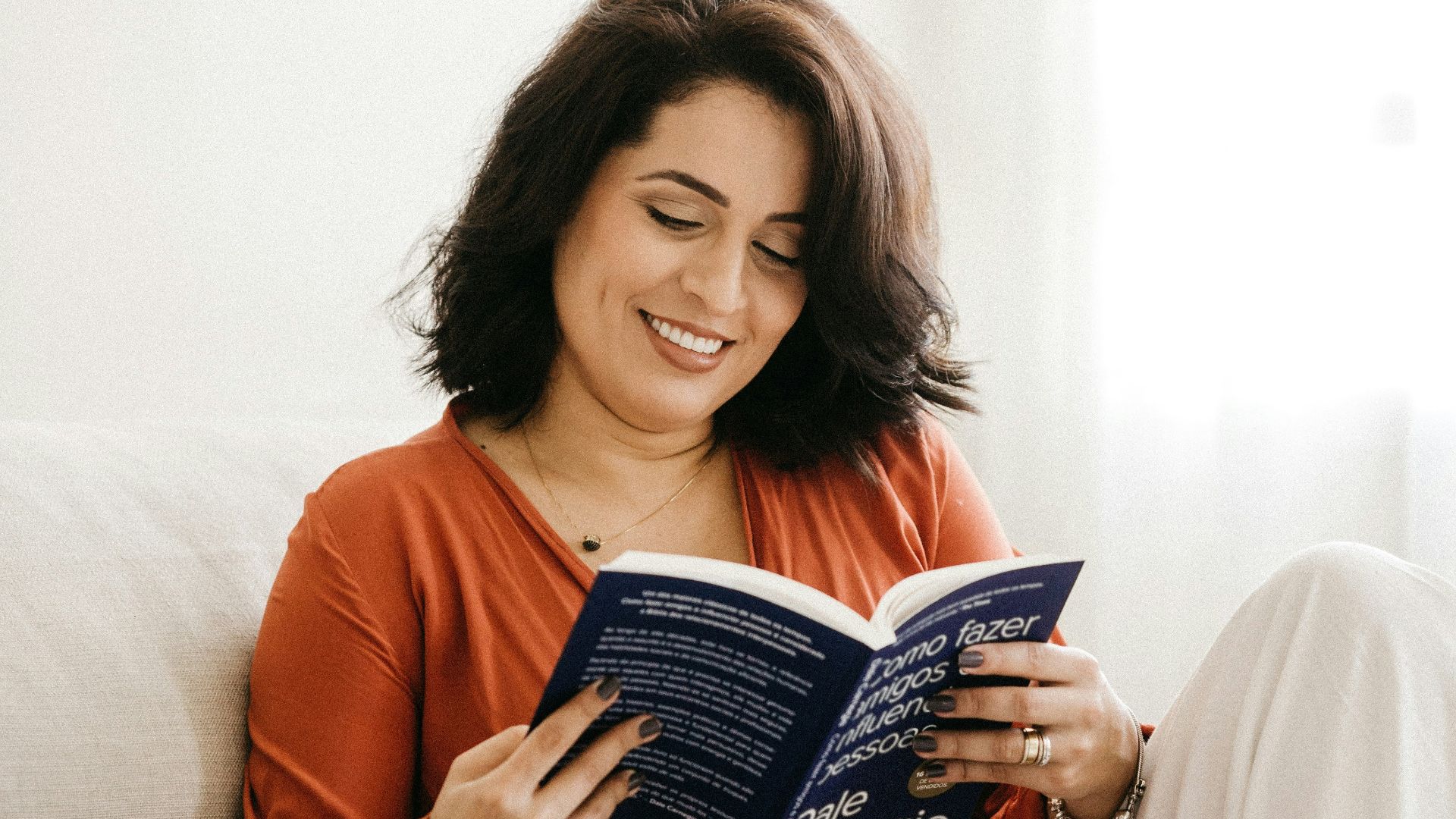 woman in orange long sleeve shirt holding blue book