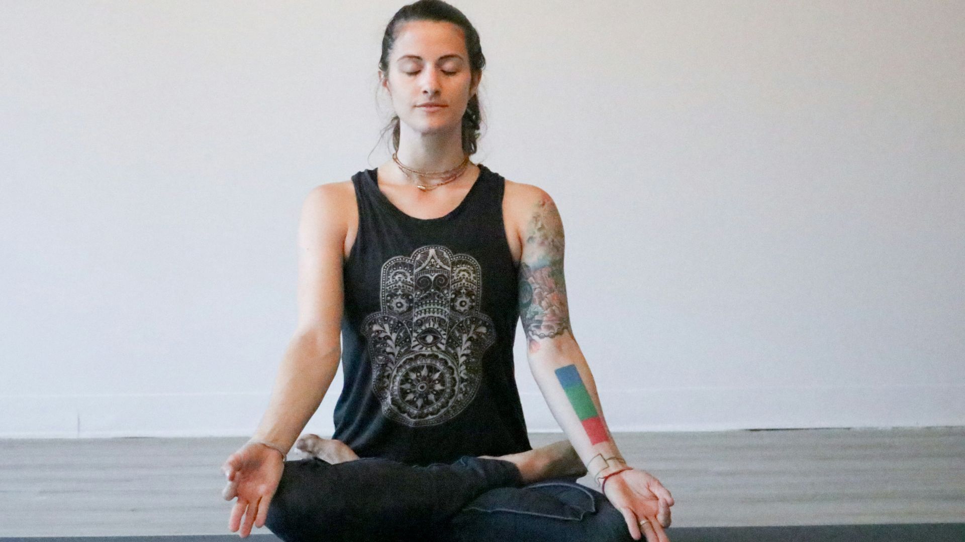 woman in black tank top and blue denim jeans sitting on black wooden bench