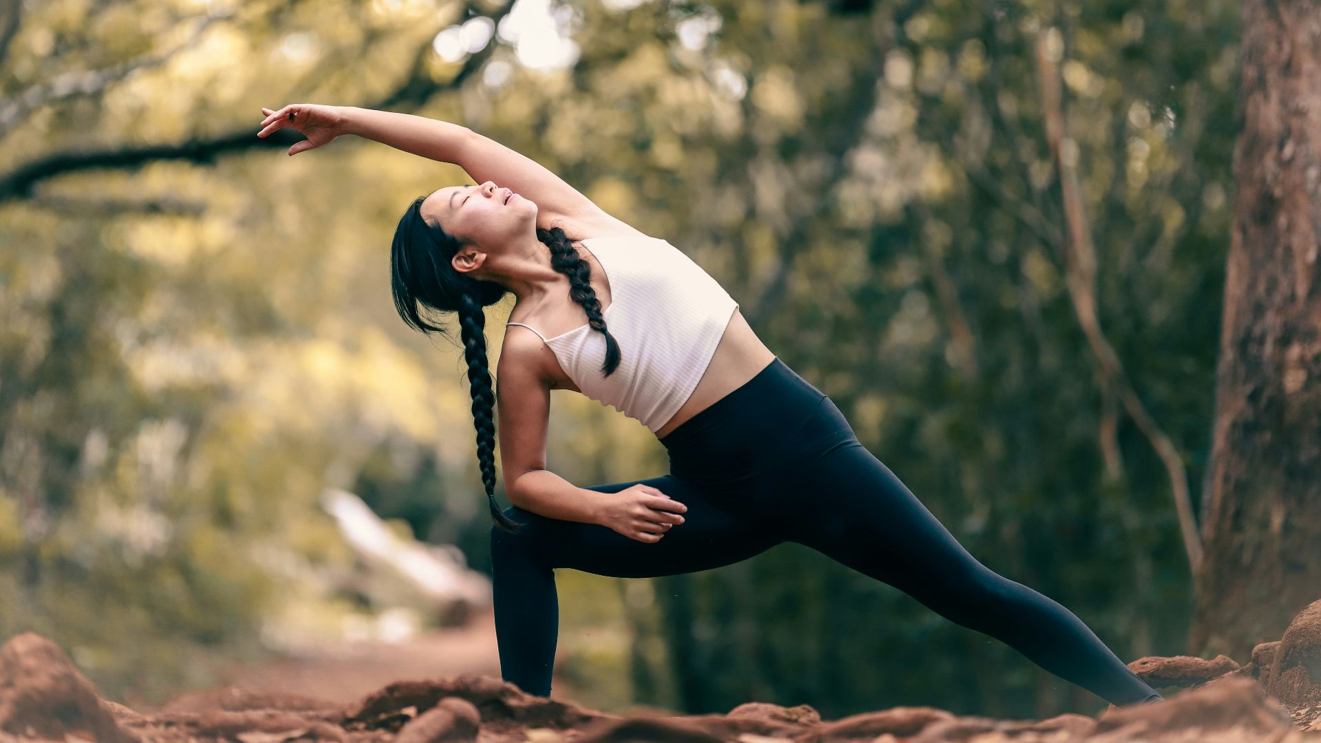 woman in white tank top and black leggings doing yoga during daytime