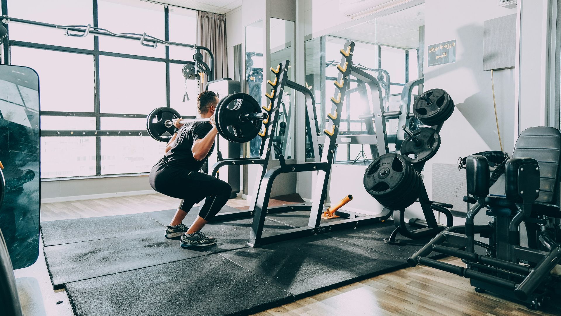 woman in black shirt and blue denim jeans sitting on black exercise equipment