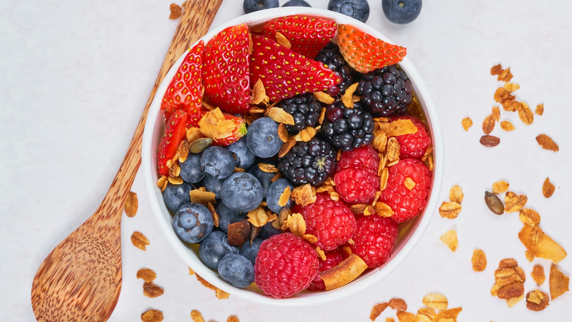 red strawberries and blue berries on white ceramic bowl
