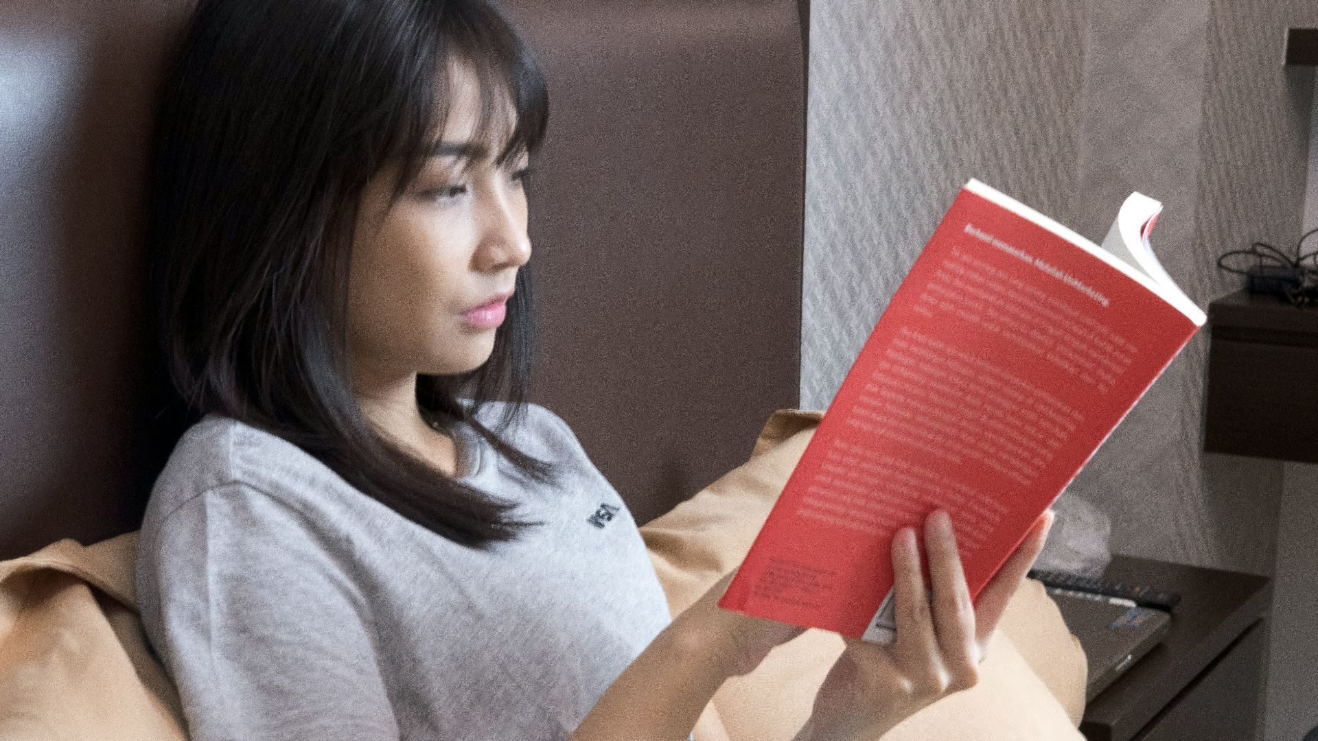 woman in gray crew neck t-shirt holding orange book