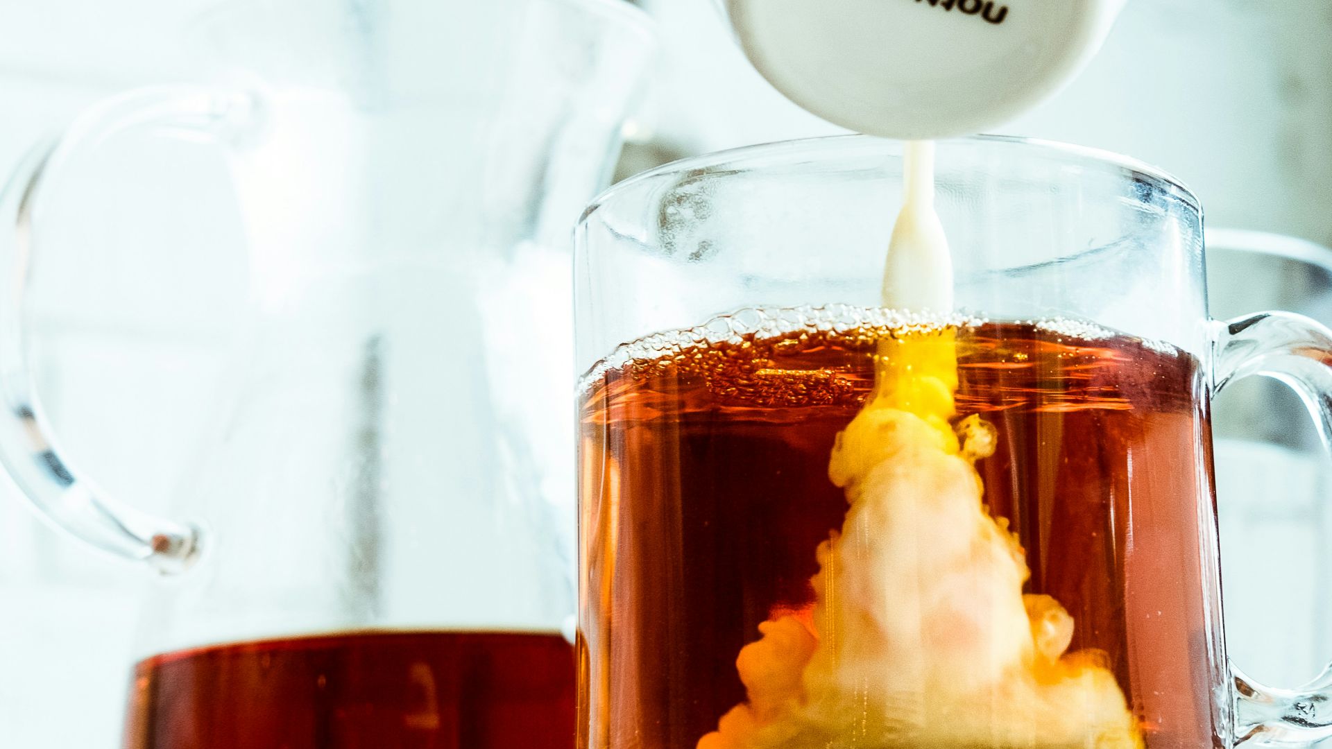 person pouring milk in tea