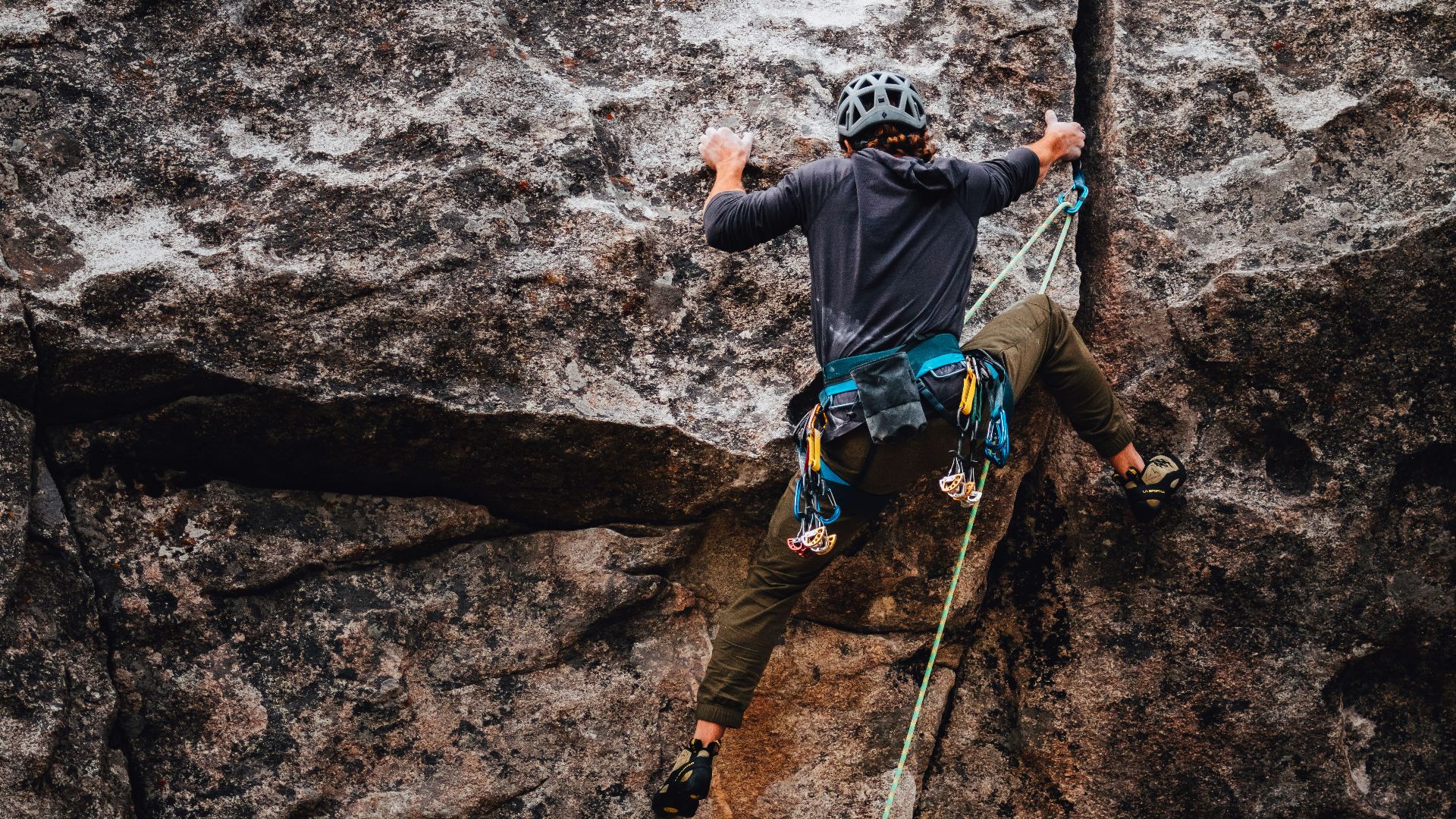 man in blue t-shirt climbing on brown rock during daytime