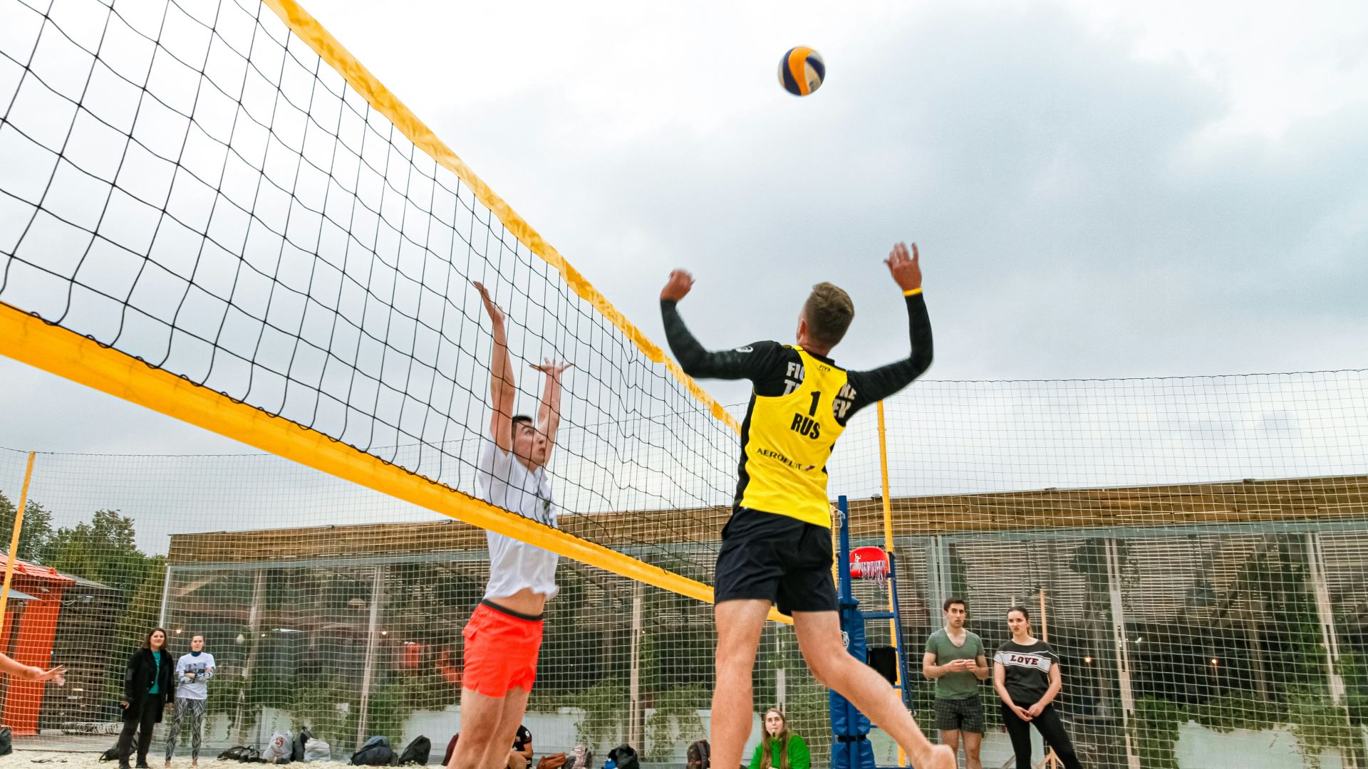 man wearing yellow and black long-sleeved shirt playing volleyball