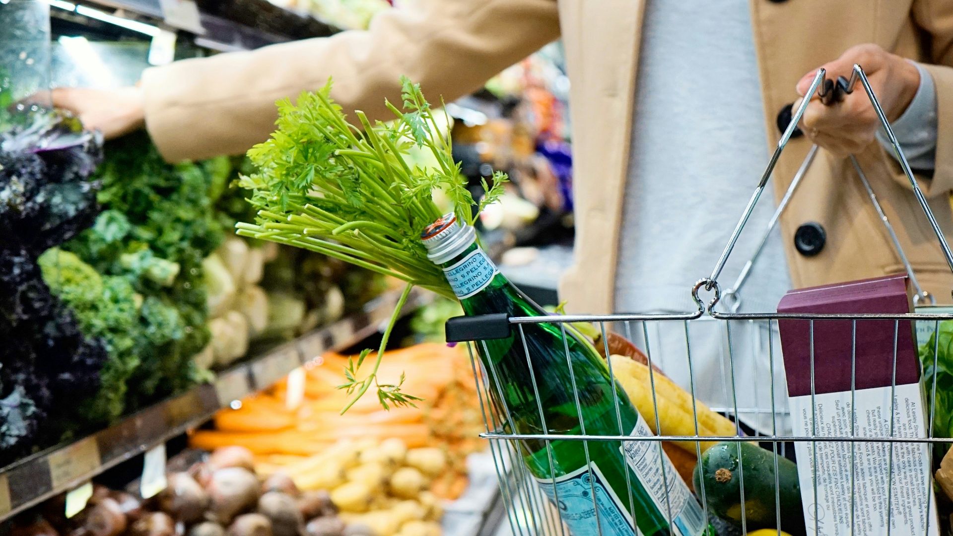 woman in white coat holding green shopping cart