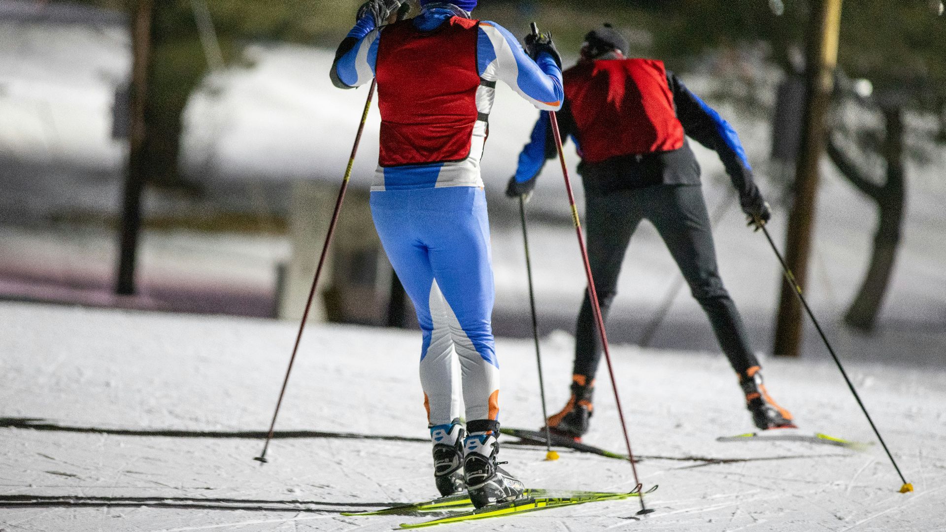 a couple of people riding skis down a snow covered slope