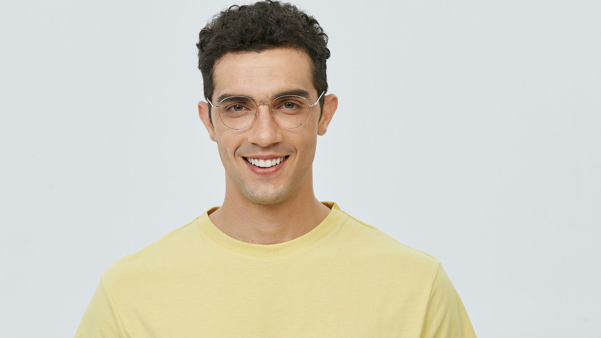 A man in a yellow t - shirt smiles at the camera