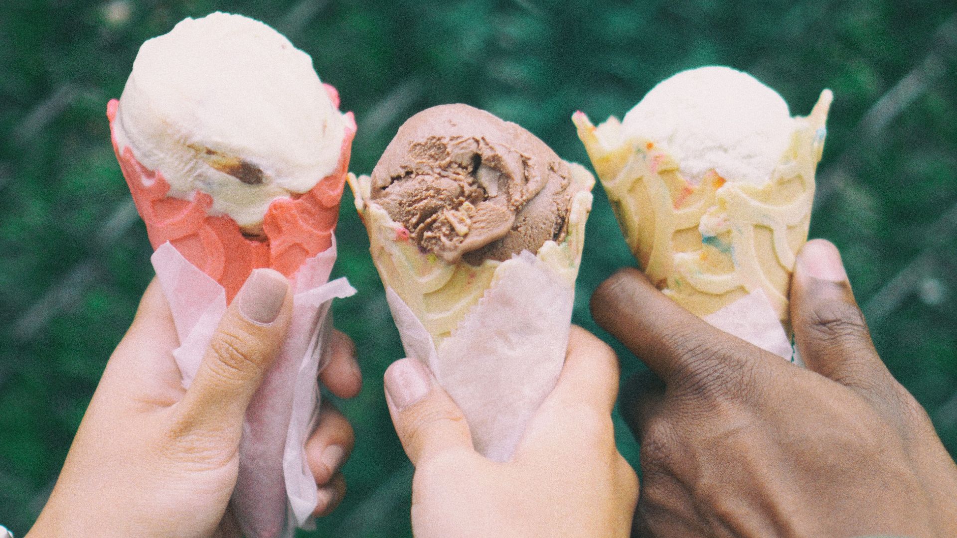 three people holding ice cream cones in their hands