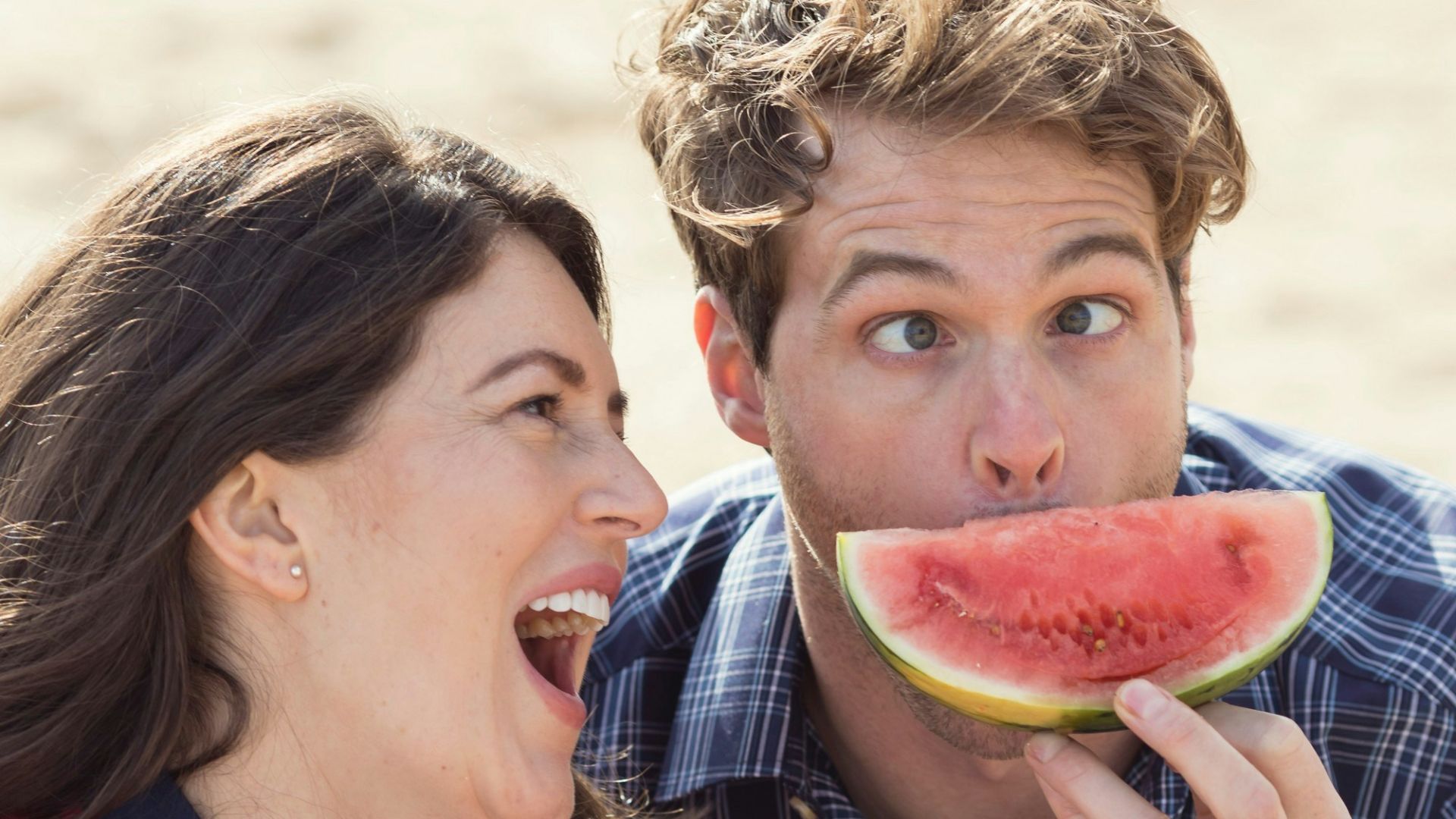 a man and a woman eating slices of watermelon