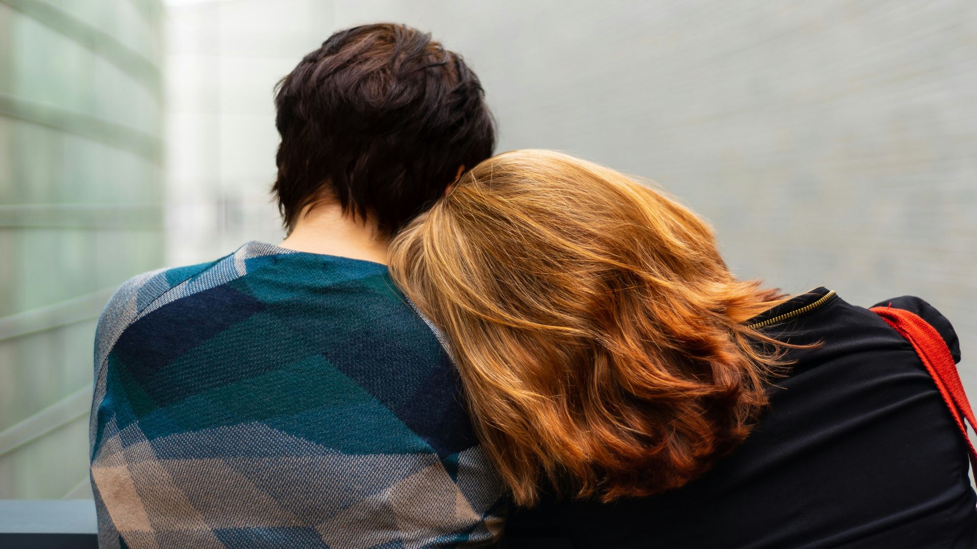 a woman rests her head on another person's shoulder