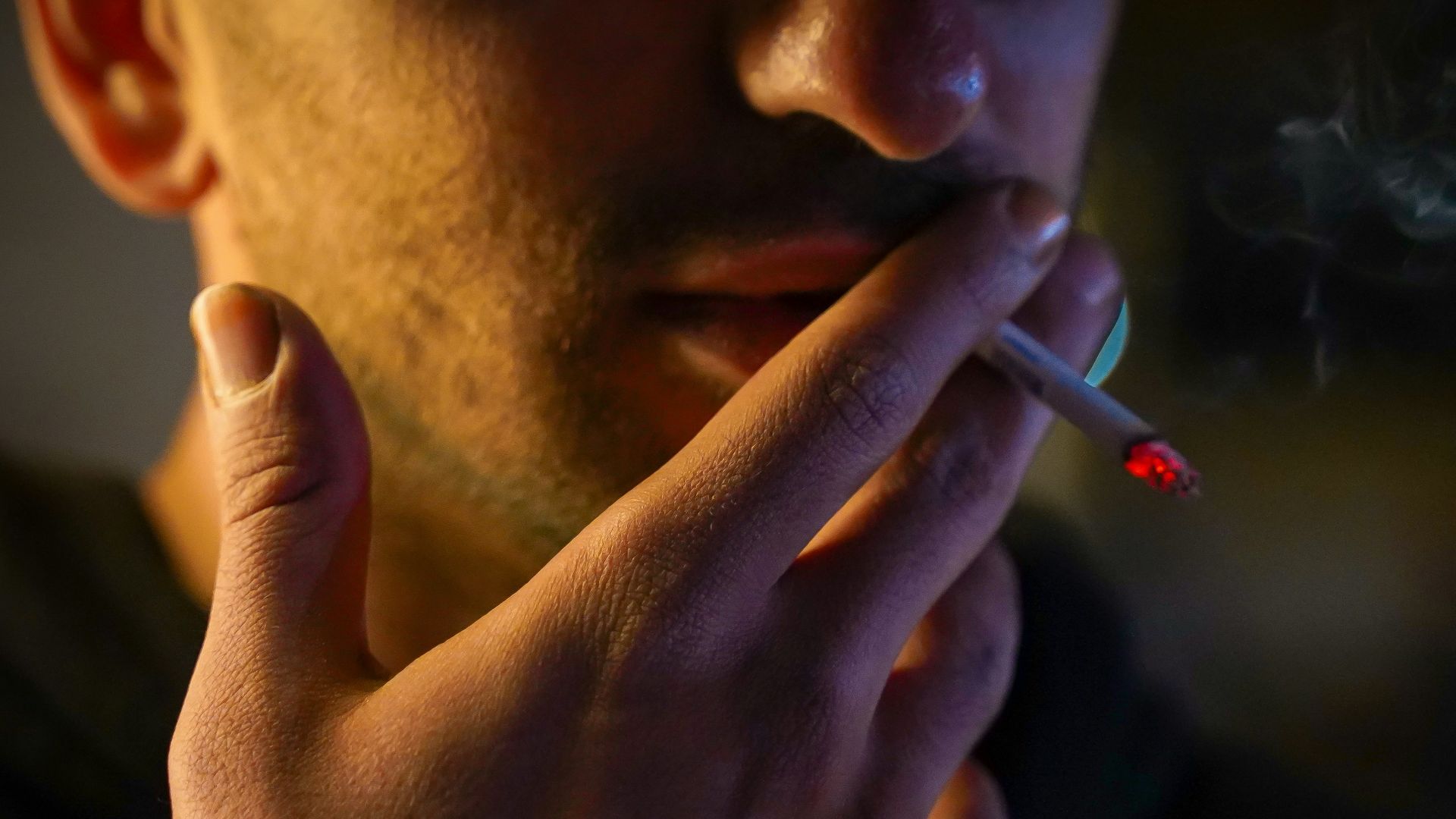 a man smoking a cigarette in the dark