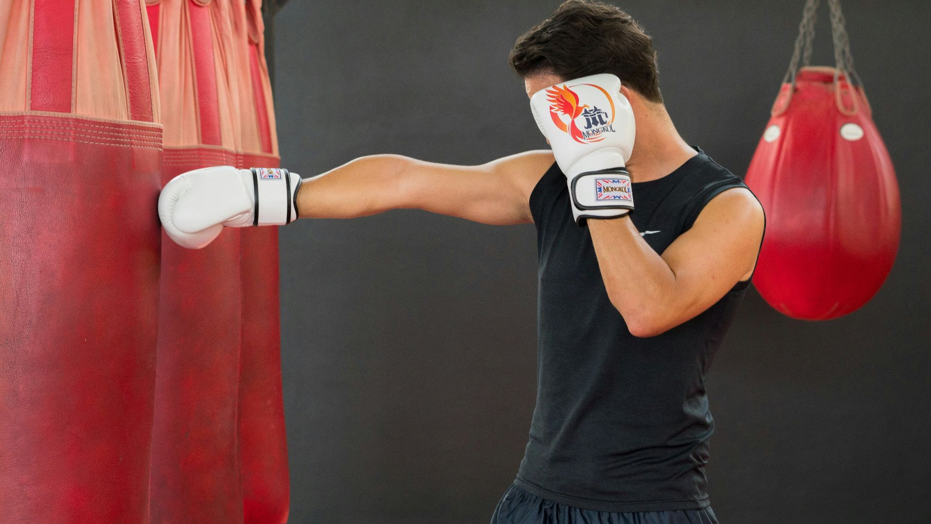 A woman in a boxing ring hitting a punching bag