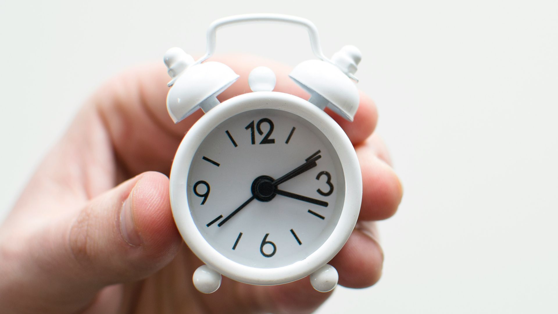 person holding white mini bell alarmclock