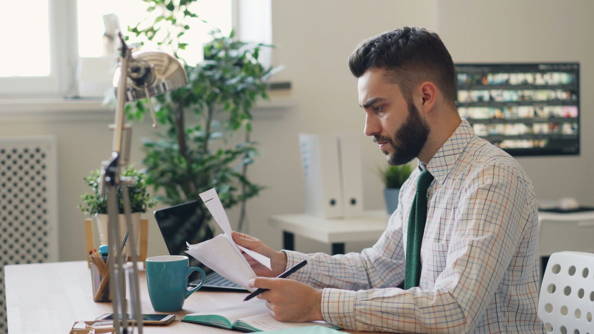 a man sitting at a desk with a laptop and papers
