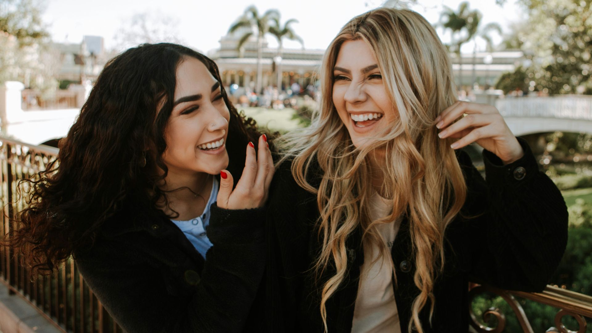 2 women smiling and standing near trees during daytime
