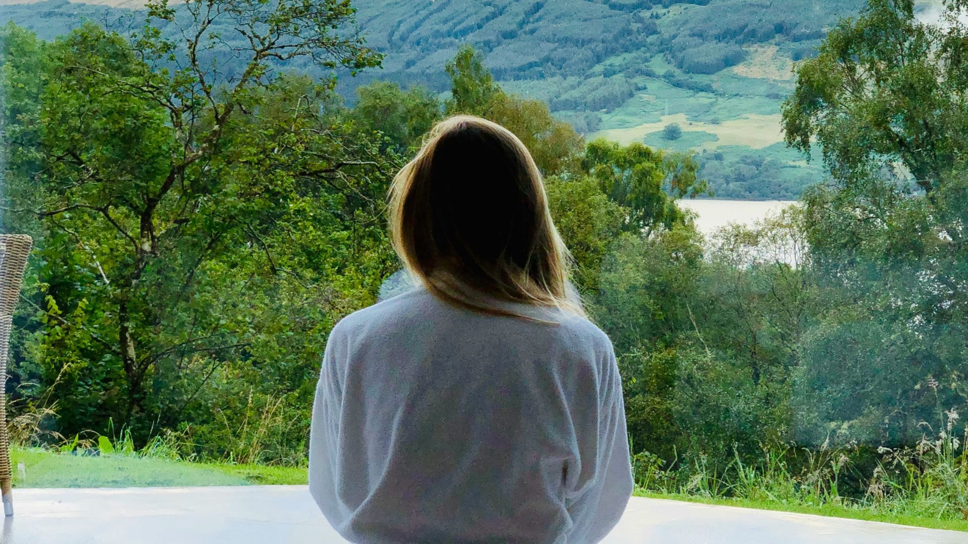 sitting woman in white robe looking at mountains during daytime