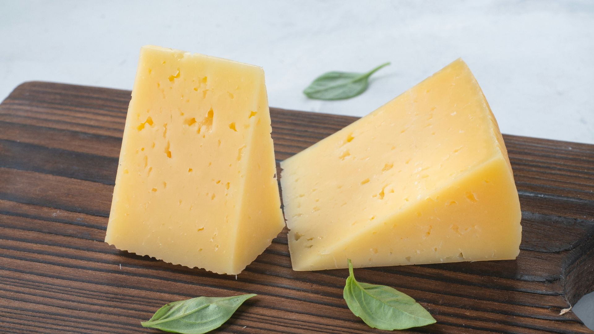 a couple of pieces of cheese sitting on top of a wooden cutting board