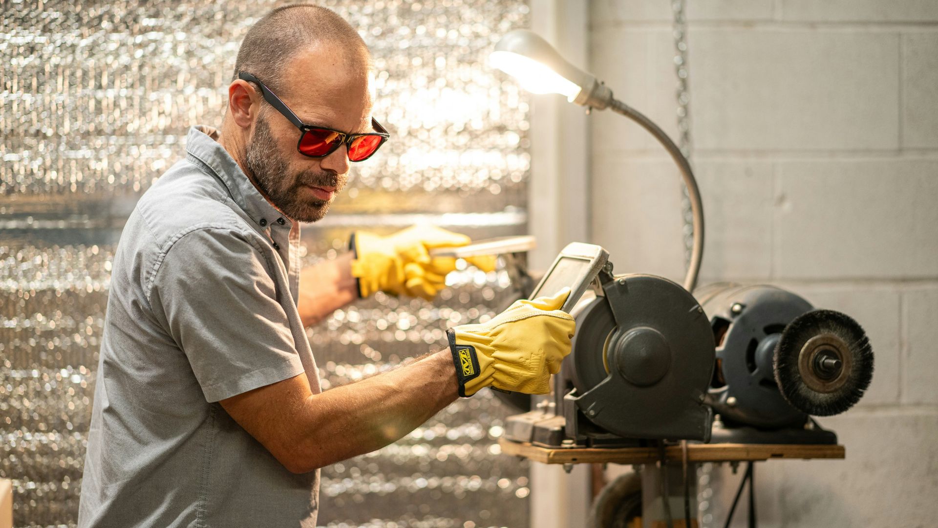 A man in a gray shirt and yellow gloves