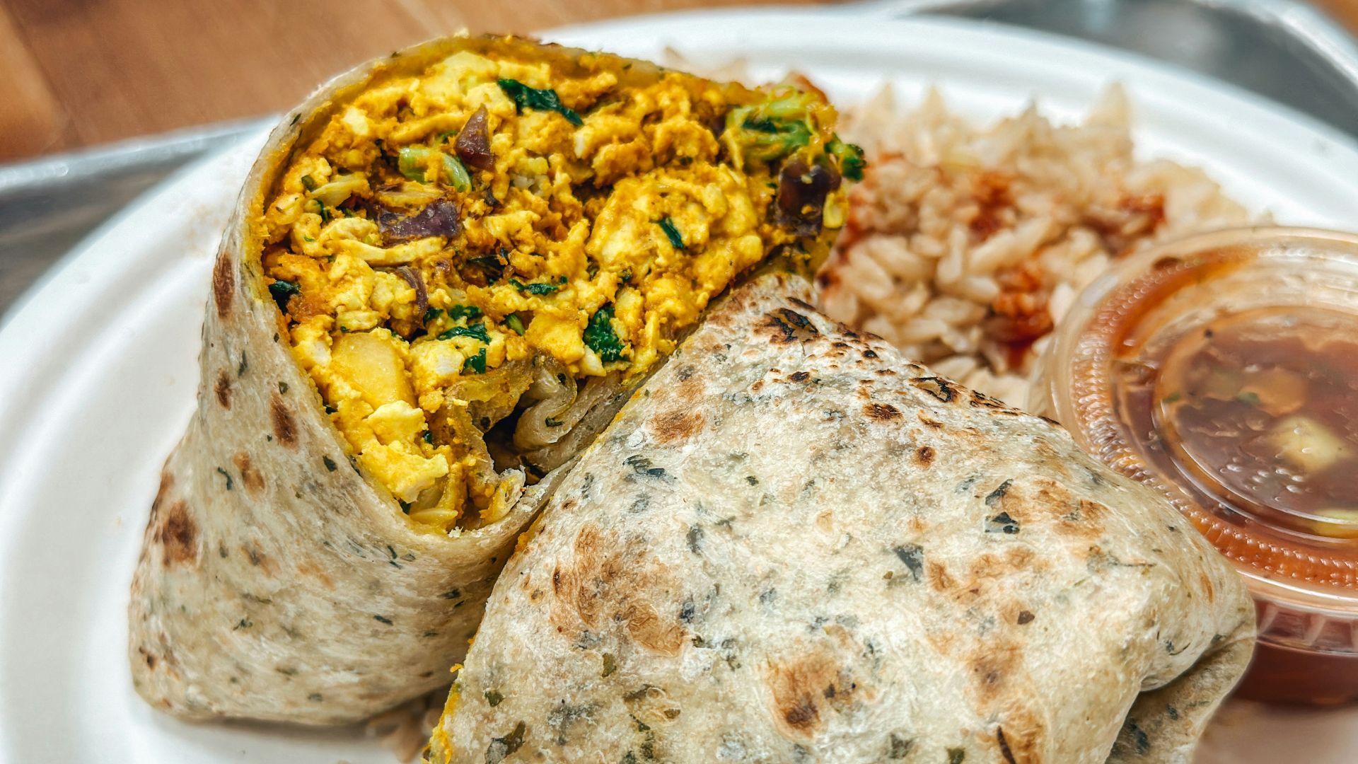 a white plate topped with a burrito and rice