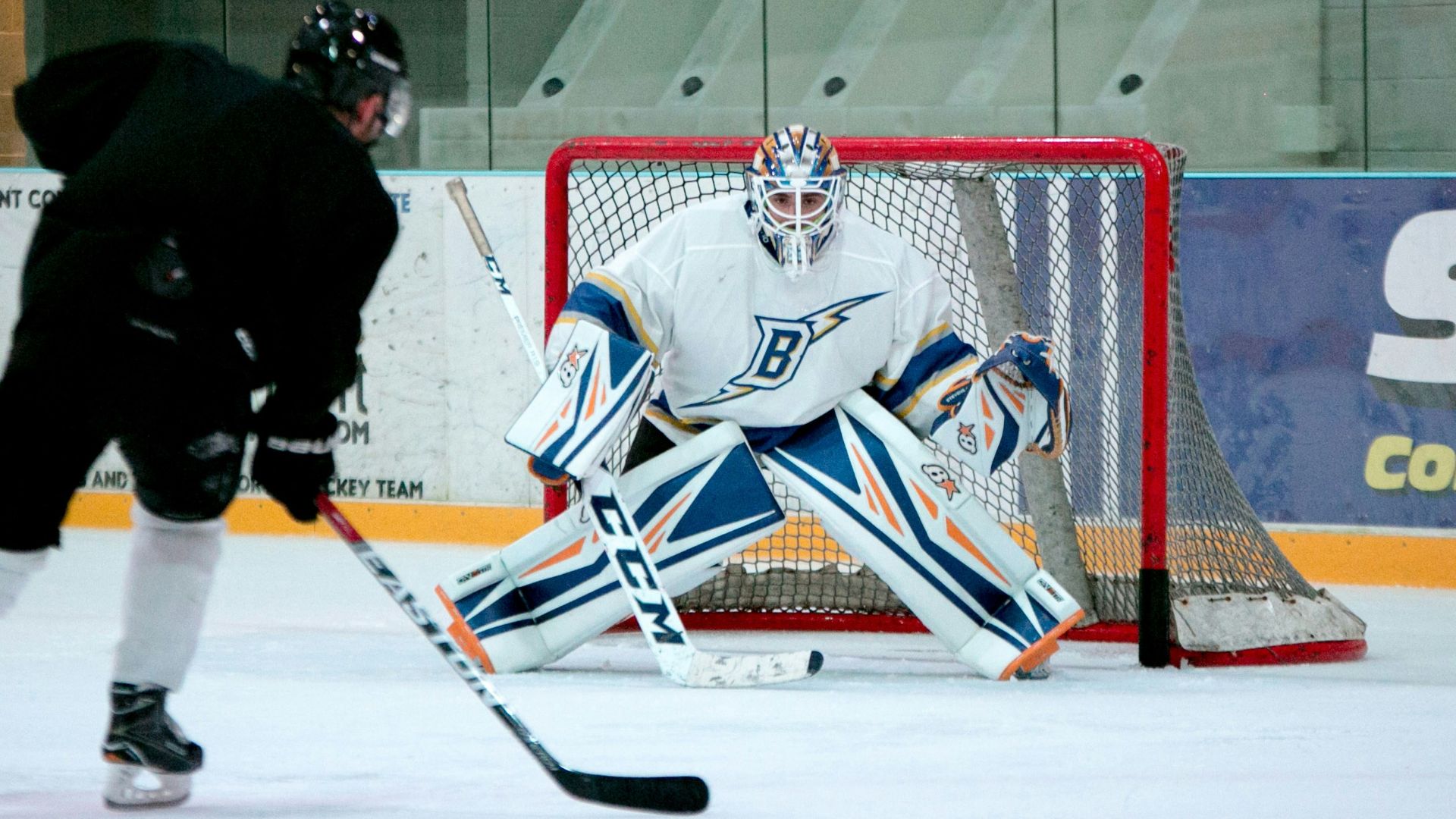 man taking aim for goal on hockey goalie