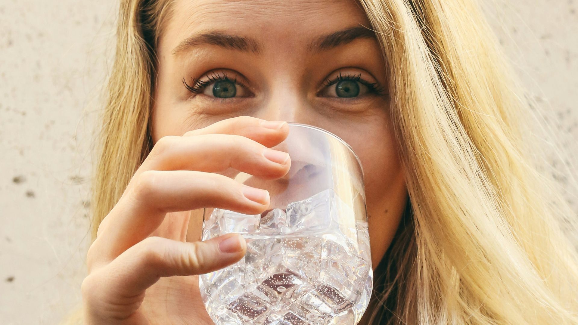 woman in white crew neck shirt drinking water