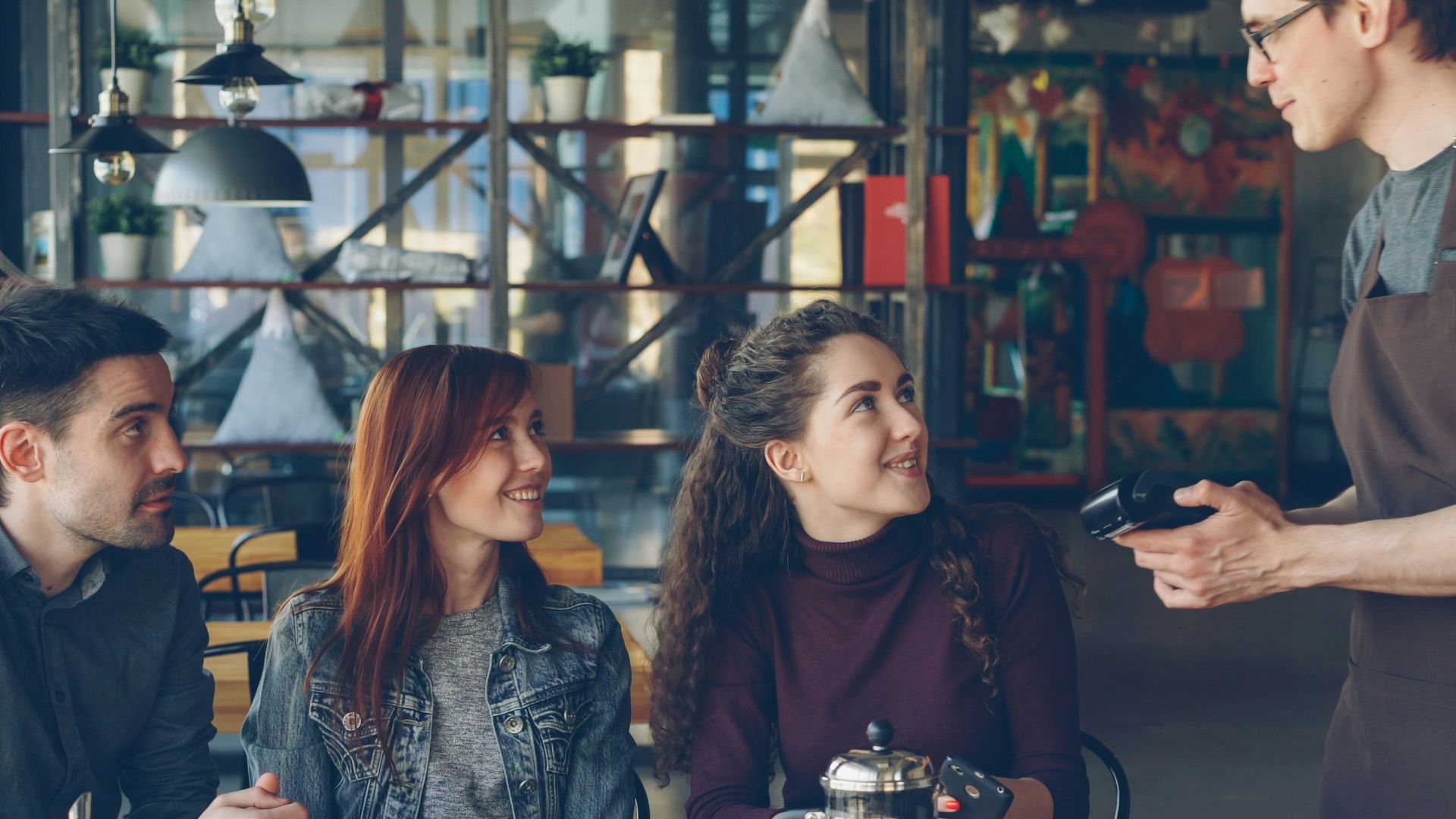 The waiter is taking payment from the customers.