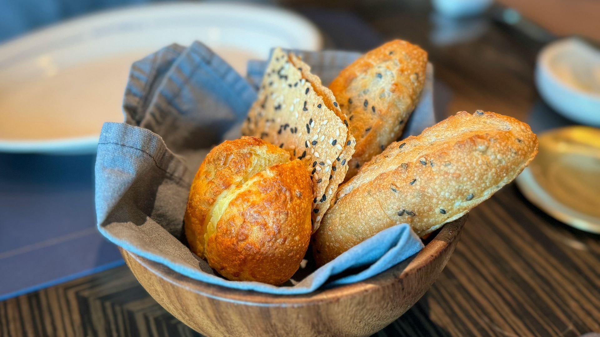 a bowl filled with loaves of bread on top of a table