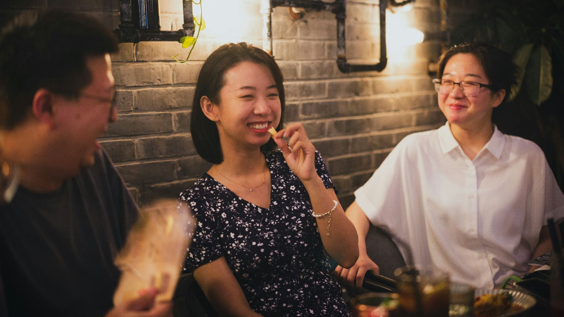 woman in black and white floral dress sitting beside man in white crew neck t-shirt