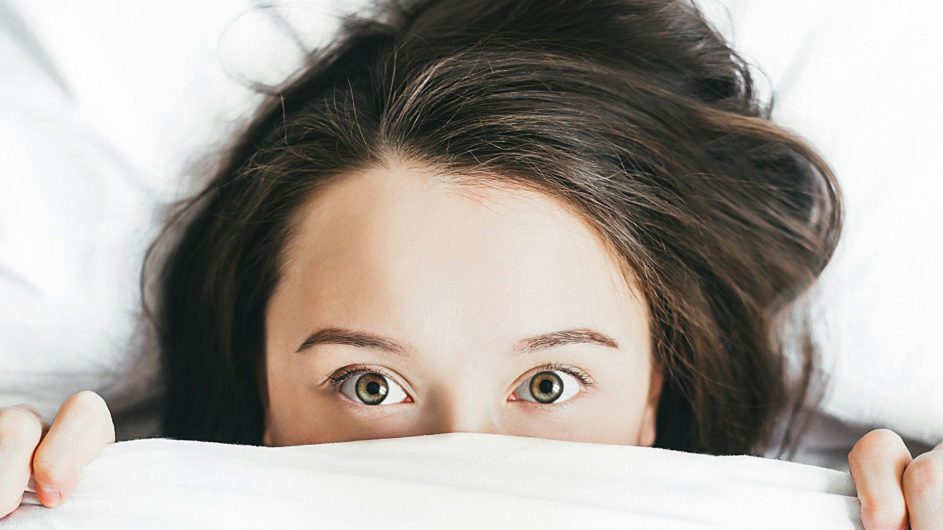 woman covering her face with blanket