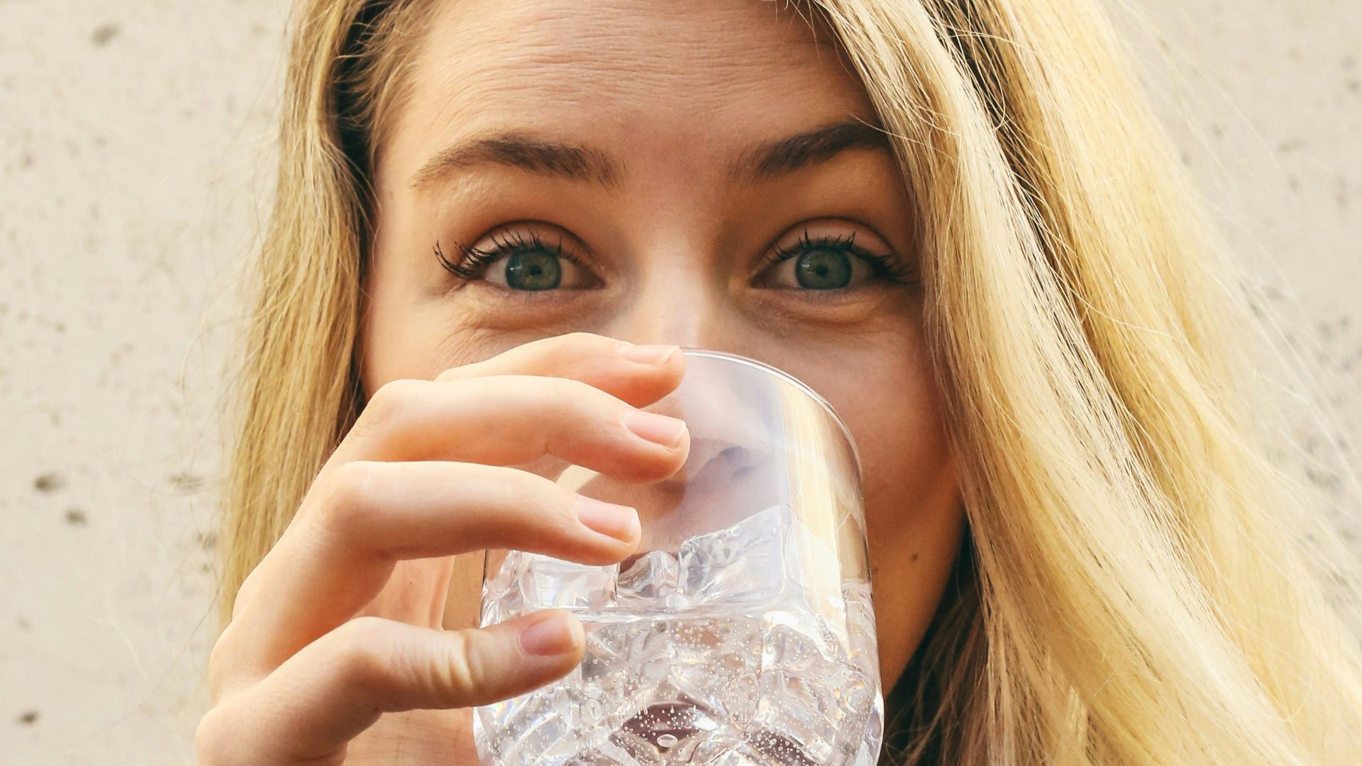 woman in white crew neck shirt drinking water