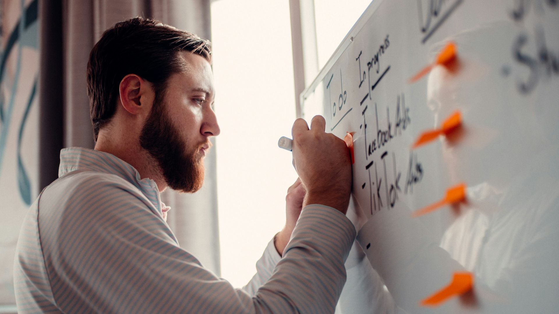 a man writing on a white board with orange markers