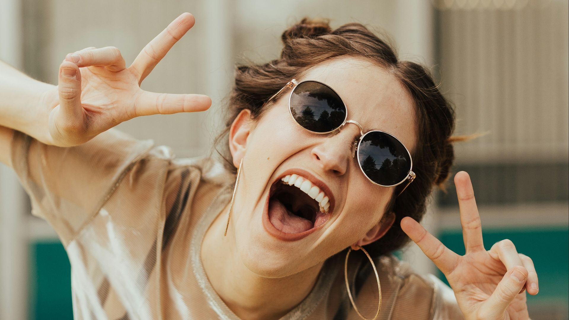 selective focus photography of jolly woman using peace hand gesture