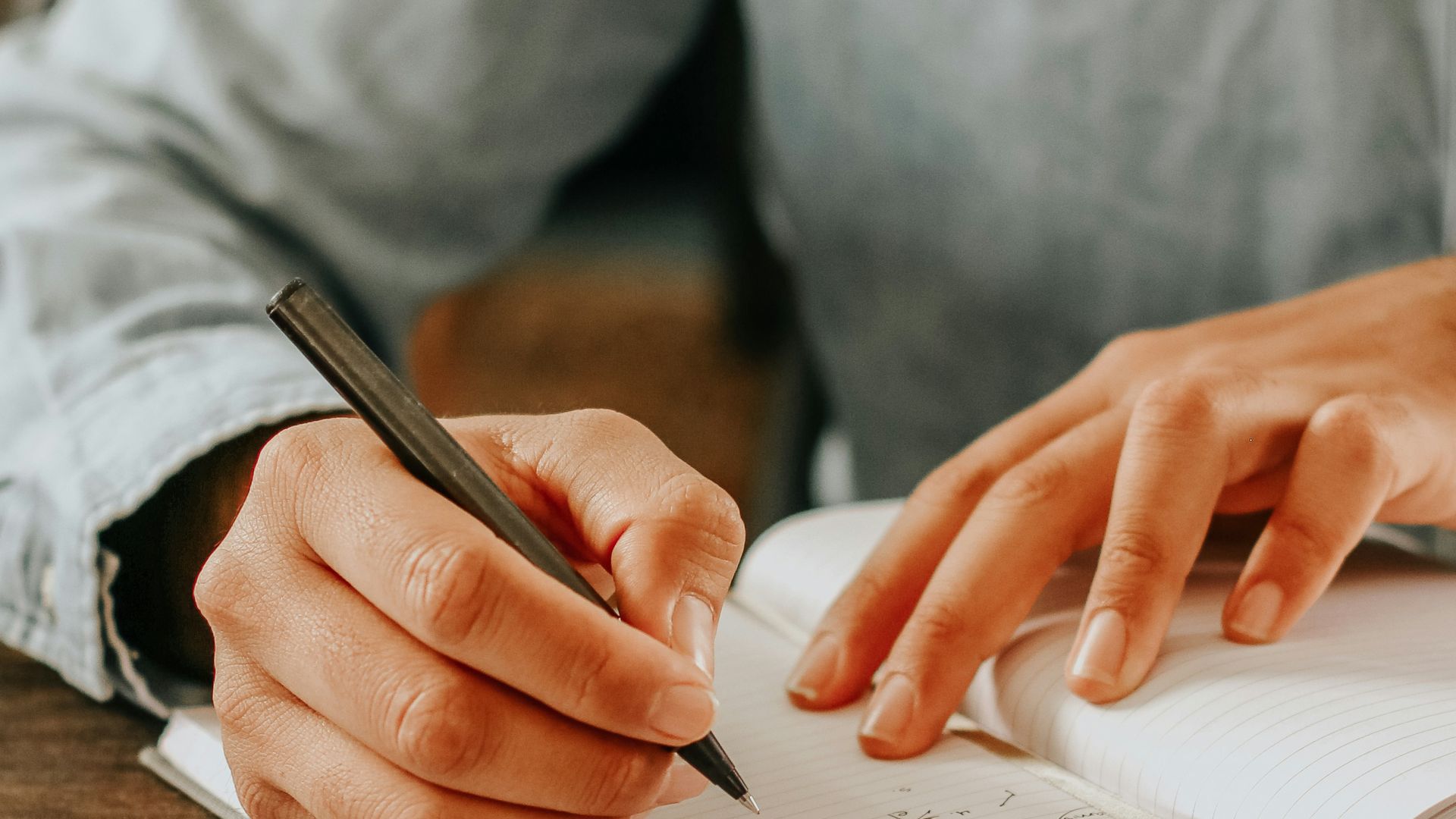 person in gray dress shirt writing on white paper