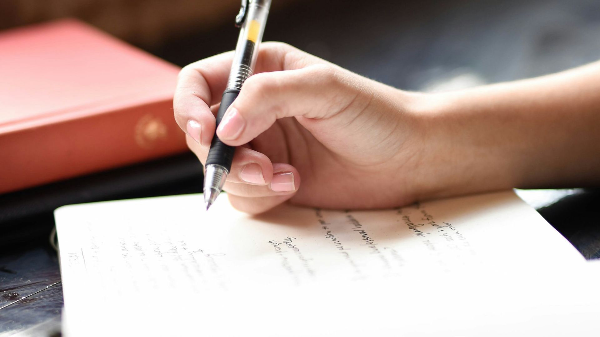 a person writing on a piece of paper with a pen