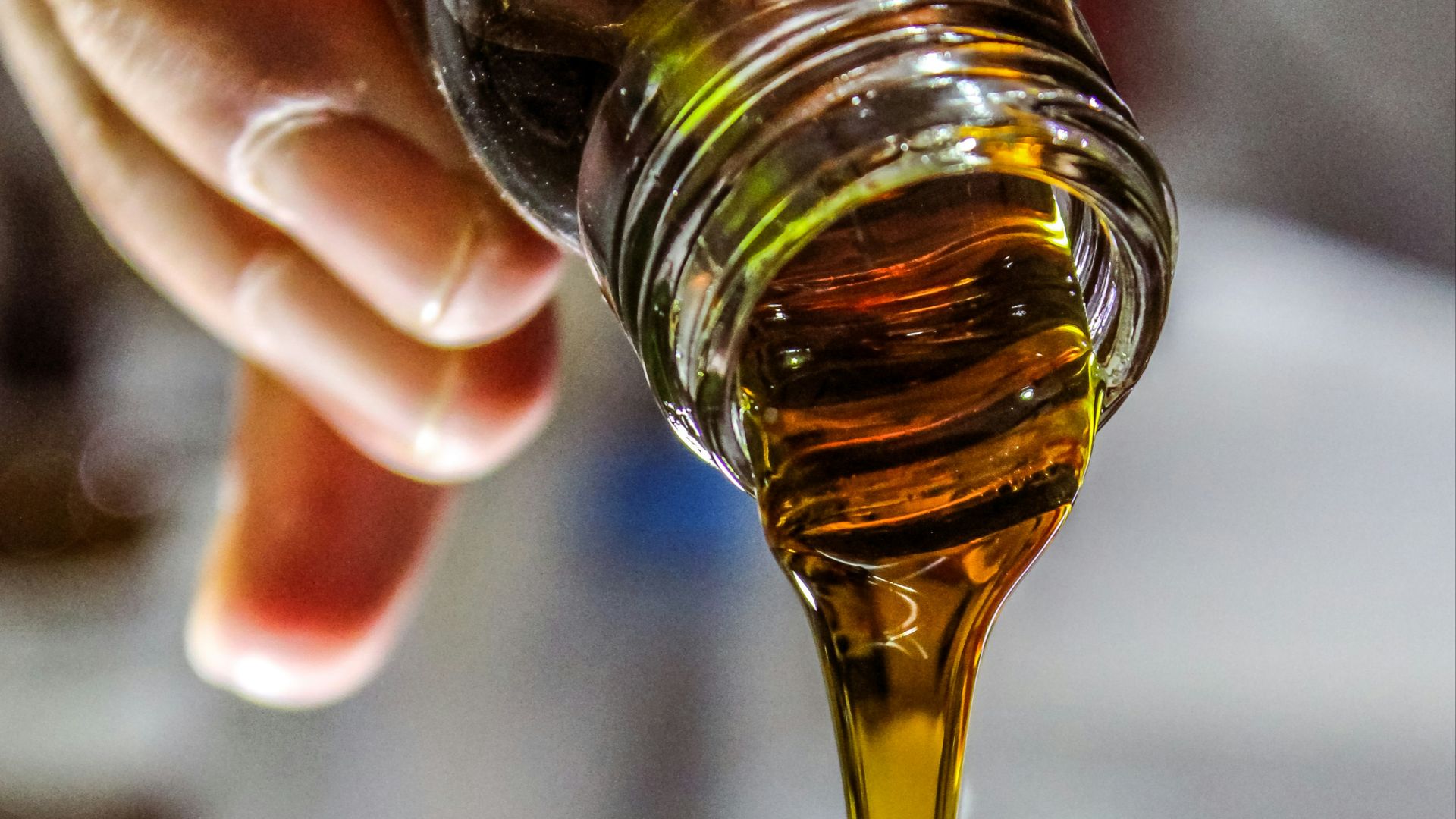 person holding clear drinking glass with brown liquid
