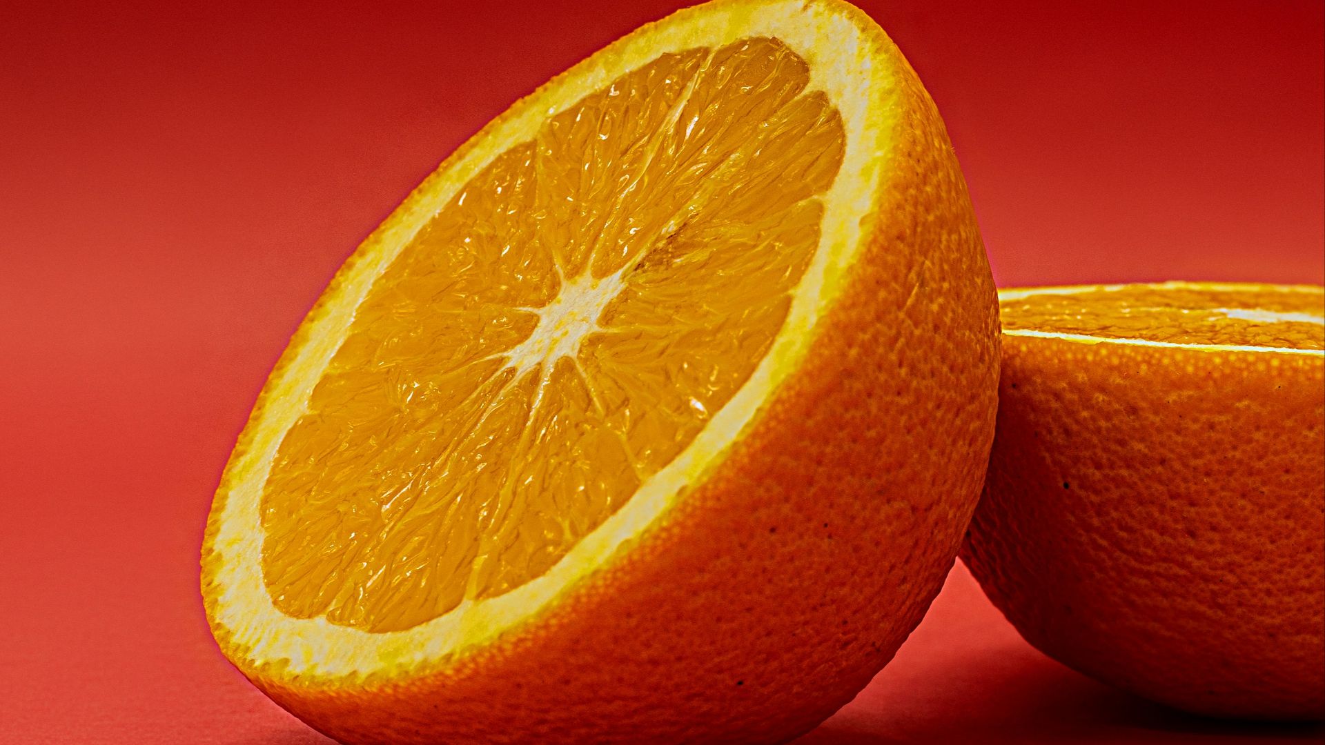 sliced orange fruit on red surface