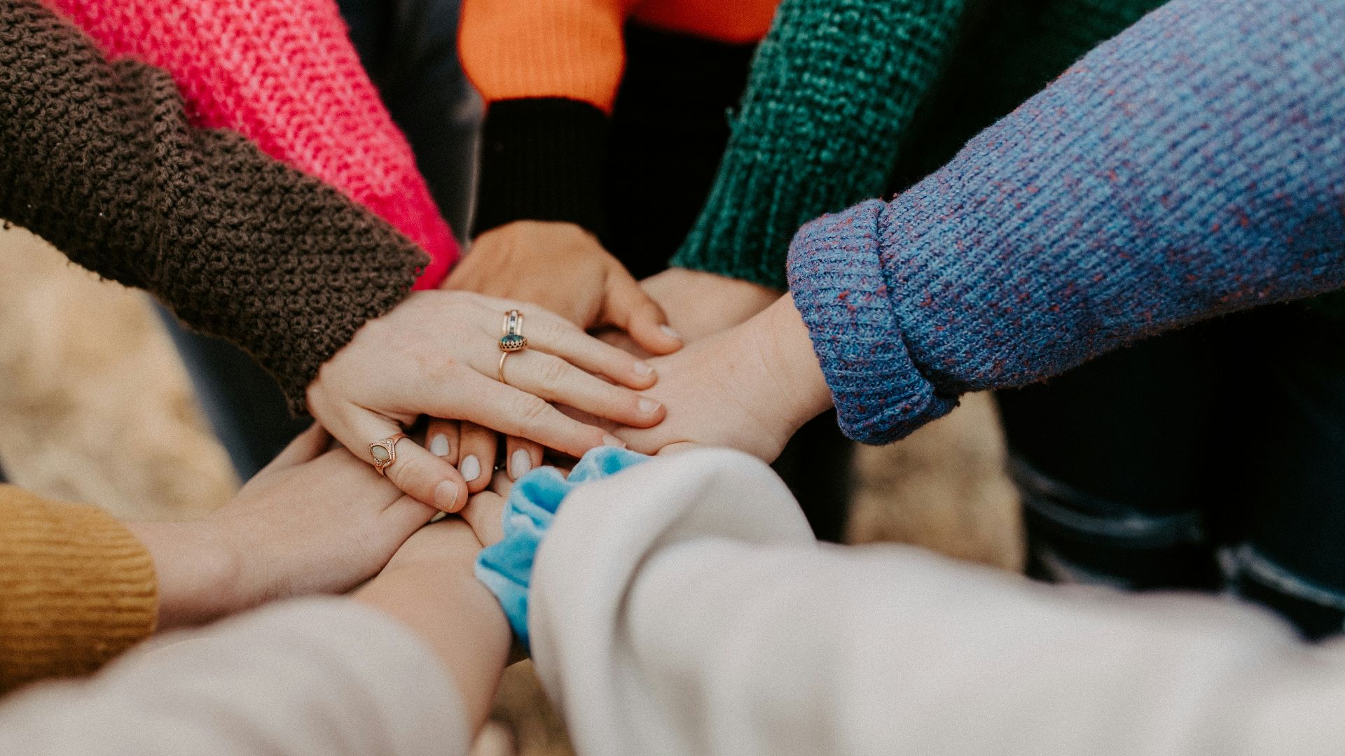 person in red sweater holding babys hand