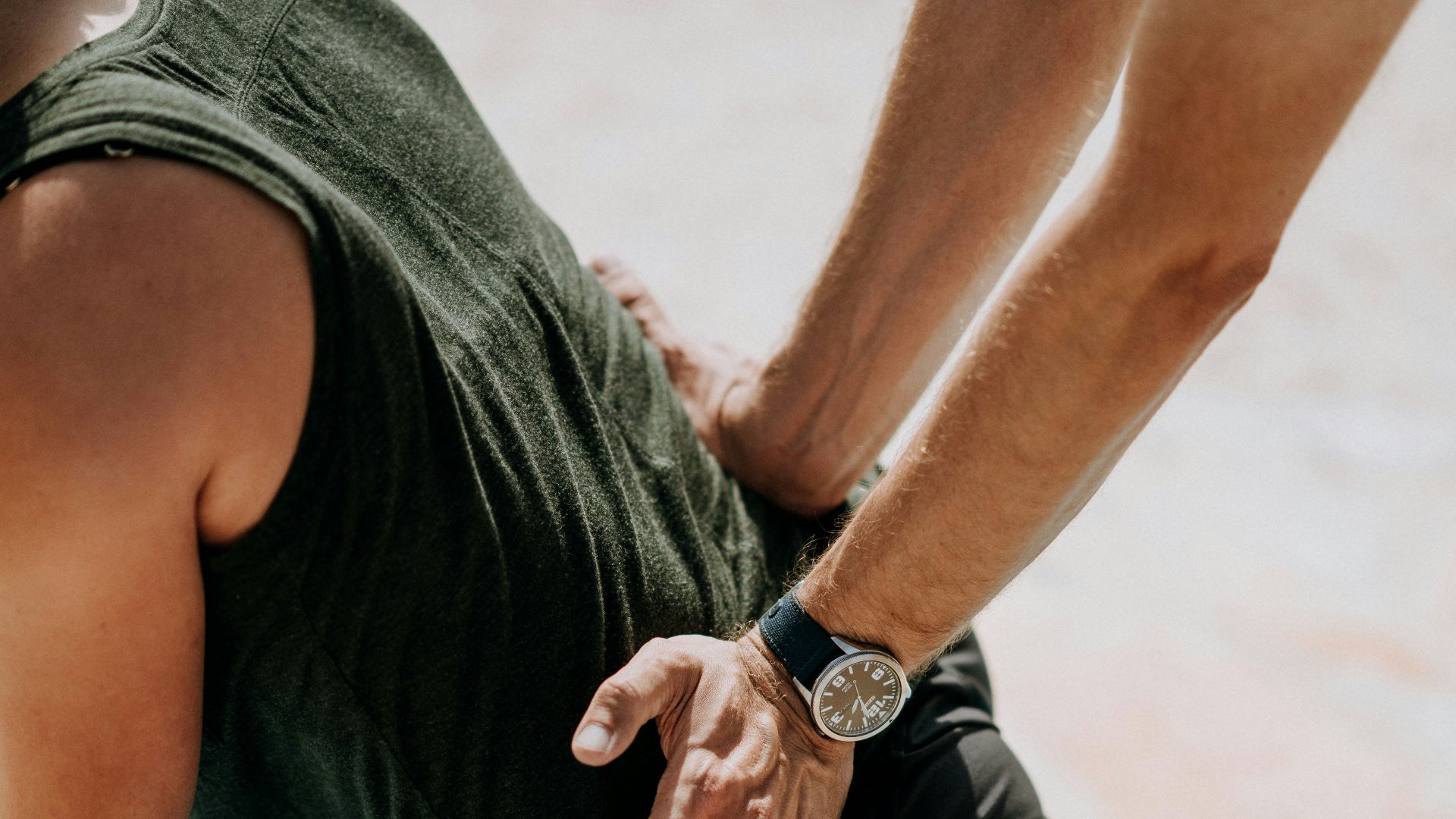 person pressing man back kneeling on blue towel