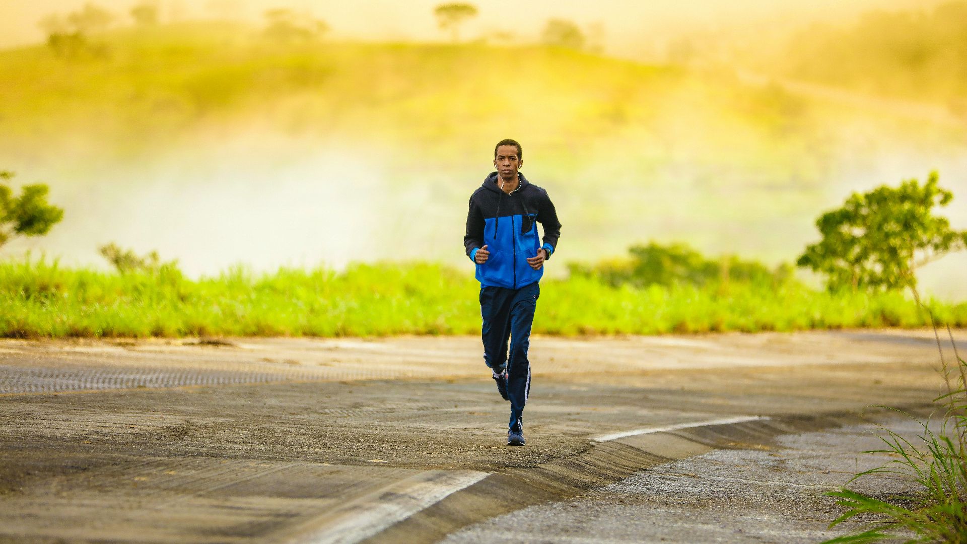 man in track suit jogging on concrete road